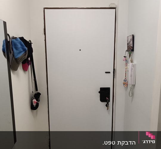 דלת לבנה עם מסגרת חומה, מנעול ומפתחות תלויים
